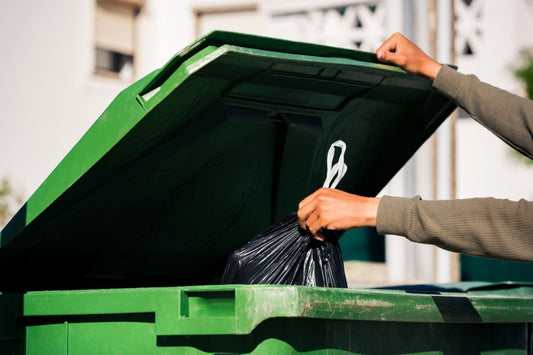 Green bin with someone adding trash