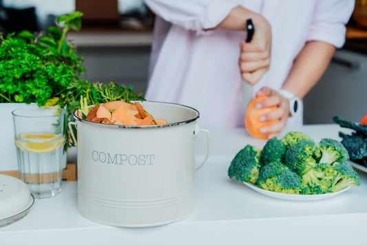 A white compost bin with a person chopping vegetables