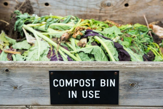 A wood bin filled with food scraps that says compost bin in use