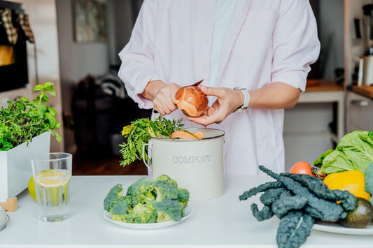 person putting food scraps in a compost bin