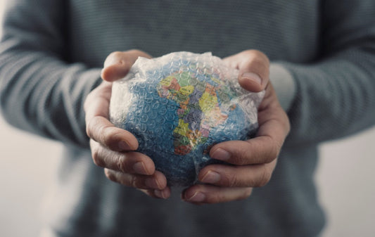 A man holding a small globe covered with bubble wrap