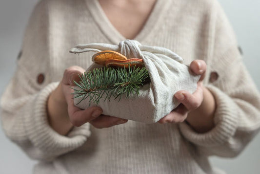 Woman holding gift wrapped in cloth with pine and dried fruit