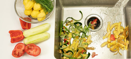 A woman peeling vegetables into a garbage disposal