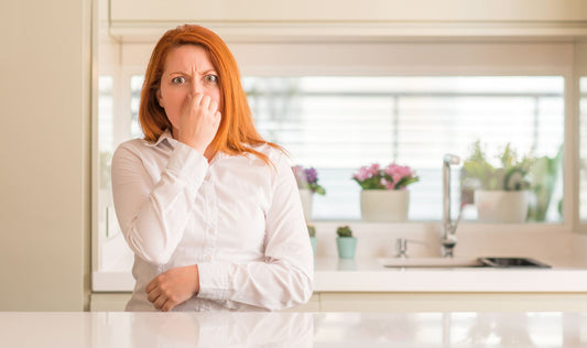 A woman plugging her nose in the kitchen