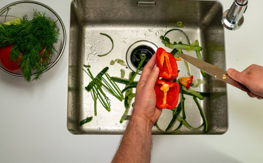 A person peeling veggies in the sink