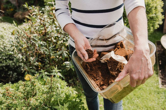 A woman with a container of compost in the garden