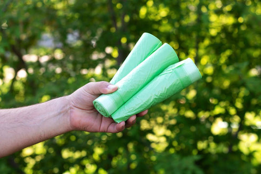 Someone holding three rolls of compostable bags
