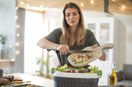 Woman throwing food scarps into a composter