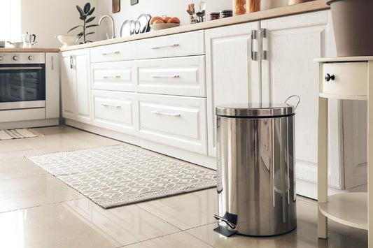 A stainless steel garbage can in a pretty white kitchen