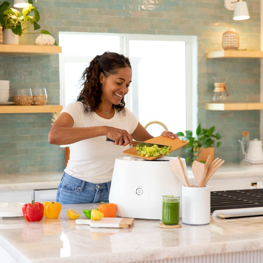 Lomi in the kitchen next to plants and cut vegetables