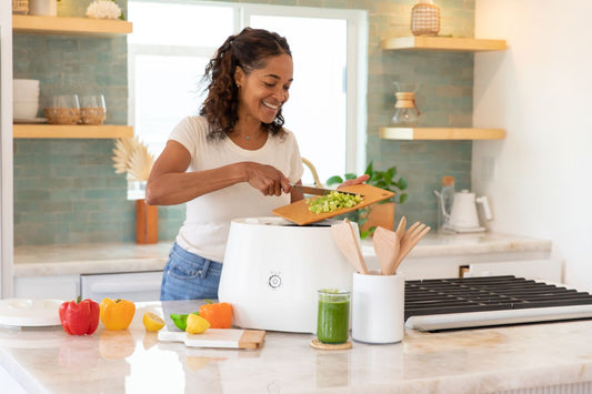 woman adding kitchen scraps from cutting board into Lomi