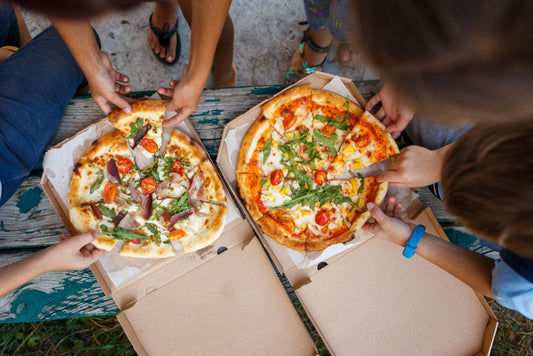 Group of people eating pizzas from boxes