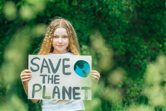 A girl holding a sign that reads save the planet