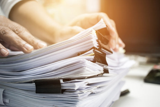 A man looking through several stacks of white paper