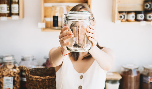 Woman holding up an empty jar in zero waste kitchen